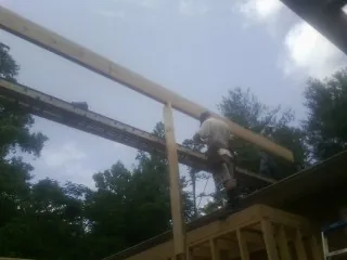 Carpenter setting a ridge beam over a new addition frame — Ice Dam Removal by Roofing Brothers in Bairdford