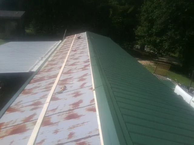 Old rusted panels beside newly installed green metal roofing — Wind Damage Roof Repair by Roofing Brothers in Bairdford
