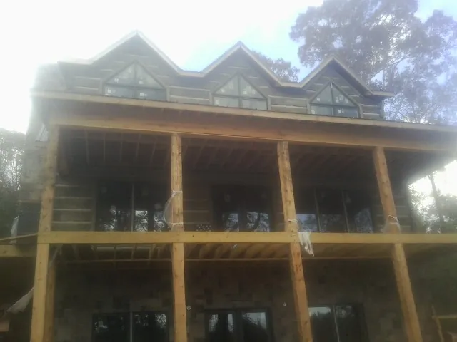 Dormers and porch framing on a large log home under construction — Roof Coating work by our crew in Bairdford