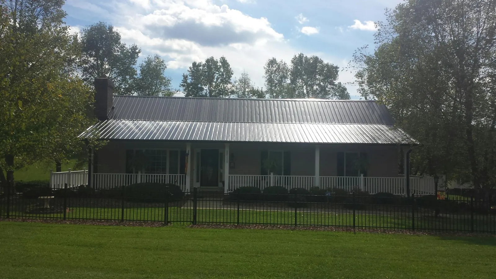 Gray metal roof on a brick ranch with a full width front porch — Gutter Guard Installation work by our crew in Bairdford