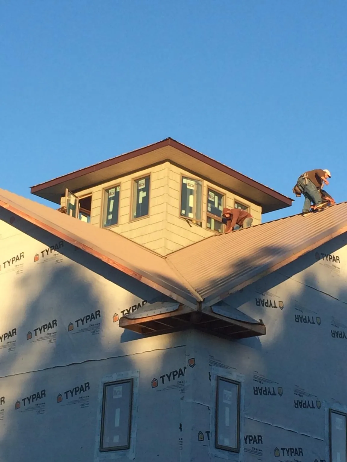 Roofers working around a rooftop cupola on a new metal roof at sunset — Roof Waterproofing in Bairdford by Roofing Brothers